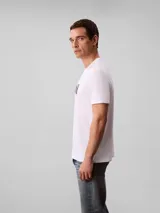 Remera Calvin Klein de color blanco, de corte regular y manga corta, con cuello redondo. Cuenta con un estampado gráfico artístico de la marca en el pecho en tonos negros y detalles en rojo.