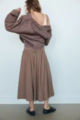 Camisa de manga larga con cuello solapa y diseño de cuadros pequeños. Presenta mangas con pliegues y cierre frontal con botones ocultos.
