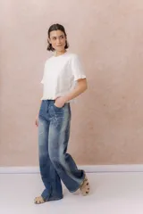 Jean de tiro medio y pierna amplia, con calce wide leg y lavado azul con efecto desgastado. Presenta estampado floral y de mariposas en toda la prenda, bolsillos delanteros y traseros, y cierre frontal.