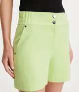 Bermuda roja de poliéster con cintura elástica, bolsillos laterales y cierre con cremallera y botones.