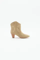 Bota corta estilo texano con taco medio de 6 cm. Confeccionada en cuero gamuzado, presenta recortes laterales que emulan la forma de una mariposa. Diseño de punta fina y caña media.
