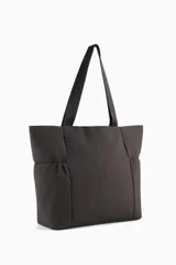 Bolso tipo shopper Puma Up de color negro, con asas de hombro y el logo de la marca en dorado en la parte frontal.