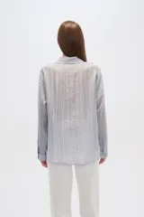 Camisa celeste de lyocell con textura arrugada, corte holgado, cuello clásico y cierre frontal con botones.