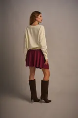 Sweater tejido color marrón claro, de escote redondo y calce holgado. Tiene hombros caídos, mangas largas y puños tejidos.