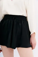 Short negro de corte holgado con cintura elástica y cordón ajustable. Presenta un diseño fluido y ligero.