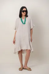 Vestido midi de lino color beige, con mangas cortas, cuello redondo, alforzas verticales en el pecho y detalle de volados en el ruedo.