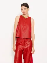 Top corto sin mangas color rojo, confeccionado en cuero vacuno con detalle de trenzado en el delantero y espalda cruzada con abertura.