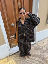 Pantalón de corte recto y holgado, confeccionado en tela de viyela con estampado de cuadros en tonos negro, gris y blanco. Presenta cintura elástica para mayor comodidad.