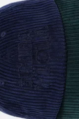 Gorra de béisbol confeccionada en pana, con diseño bicolor que combina una corona azul marino y una visera verde oscuro. Presenta un bordado tonal en el frente y ojales de ventilación.