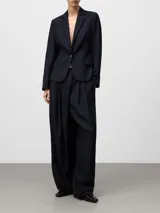Pantalón sastre de pierna ancha en color azul marino, con pliegues delanteros y cierre cruzado. Incluye bolsillos laterales y bolsillos de vivo en la parte posterior, confeccionado en una mezcla de poliéster, lana merino y viscosa.