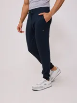 Pantalón deportivo tipo babucha color azul marino, confeccionado en 60% algodón y 40% poliéster, con cintura elástica ajustable con cordón y puños ajustados.
