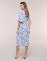 Vestido midi de calce holgado y caída fluida con escote en V cruzado, cintura elastizada fruncida y mangas cortas con volados superpuestos. Cuenta con un diseño estampado de flores grandes en tonos amarillo, blanco, azul marino y verde.