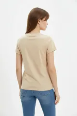 Remera de algodón color beige, de manga corta con vuelta, cuello redondo y estampa frontal de flores con lazo en tonos azules y celestes.