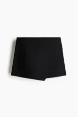 Short pollera de sarga color negro, diseño cruzado tipo envolvente en el frente y ajuste entallado.