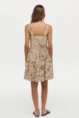 Vestido corto camel de lino y viscosa, con escote cuadrado, breteles anchos y diseño con godets. Presenta un estampado artesanal en tonos marrones y blancos.