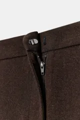 Pantalón recto color marrón oscuro, de tiro medio, con cintura elástica en la espalda, bolsillos delanteros de vivo y cierre frontal con cremallera, botón interior y gancho.