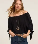 Blusa negra de viscosa con escote off-shoulder, mangas 3/4 con elásticos y lazos en los puños.