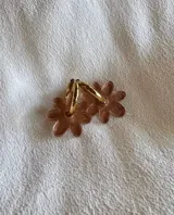 Aros de argolla metálica con dije colgante en forma de flor de acrílico color rosado.