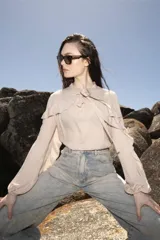 Blusa celeste de bambula con cuello con lazo y volados en el frente y mangas largas.