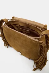 Bolso tipo bandolera confeccionado en serraje color marrón, con diseño de flecos en el contorno y detalle de tachas metálicas formando flores en la solapa. Cuenta con asa larga regulable, cierre imantado y bolsillo interior.