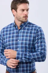 Camisa de manga larga con estampado de cuadros en tonos azules, cuello abotonado y cierre frontal con botones.