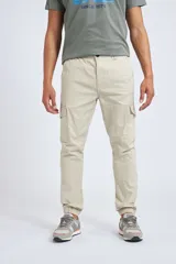 Pantalón cargo color beige con ajuste slim, cierre frontal con botón, bolsillos laterales tipo cargo y puños elásticos en los tobillos.