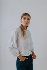 Camisa de algodón bordada color blanco con diseño floral sutil, cuello redondo, mangas abullonadas y cierre frontal de botones de nácar.