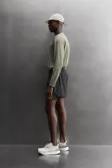Short de running 2 en 1 color beige, confeccionado en tejido técnico ligero y elástico con malla interior integrada. Presenta cintura elástica ajustable con cordón, bolsillo trasero con cierre y aberturas laterales en el bajo.