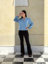 Camisa de jean celeste con cuello redondo, cierre frontal con botones y mangas largas abullonadas con puños ajustados.