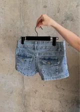 Micro short de jean tiro bajo color celeste claro, con bolsillos traseros tipo cargo con solapa y botón metálico.