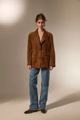 Blazer de gamuza color marrón con cuello solapa, corte holgado y detalle de tachas metálicas en solapas, bolsillos delanteros y puños.