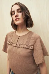 Blusa negra con textura, canesú con encaje, volados, corte fluido y mangas cortas amplias.