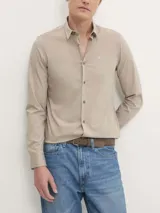 Camisa de vestir color beige claro, corte slim, de popelín de algodón elástico, con cierre frontal de botones y logo CK bordado en el pecho.