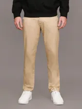 Pantalón chino color beige confeccionado en sarga de algodón elástica suave, de corte regular y pierna estrecha en el tobillo.