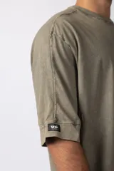 Remera oversize de algodón pesado, color gris oscuro con efecto lavado 'snow' que le da un aspecto gastado y único. Presenta cuello redondo y costuras vistas en hombros y mangas.