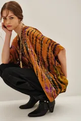 Camisa de manga corta con cuello mao y calce amplio, confeccionada en viscosa con estampado tie-dye en tonos ocre, negro y violeta. Presenta detalles bordados con mostacillas, lentejuelas, canutillos e hilos de lurex, y cierre frontal con botones a tono.