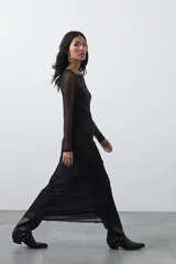 Vestido largo de manga larga confeccionado en tejido de malla transparente con sutil textura. Presenta un diseño entallado, cuello redondo y una silueta estilizada.