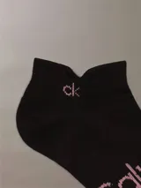 Pack de 6 medias tobilleras Calvin Klein de punto plano, color negro con logotipo de la marca estampado en color rosado.