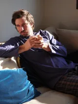 Pijama de dos piezas compuesto por una camiseta de manga larga azul marino con logo bordado en el pecho y un pantalón largo de corte recto con estampado de cuadros en tonos azul y verde.