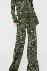 Pantalón de tricot verde militar con estampado paisley en tonos blancos y negros, tiro medio, cintura elástica con cordón ajustable y corte ancho y holgado.