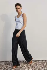 Pantalón de vestir de corte ancho y relajado, color negro con sutiles rayas diplomáticas verticales. Presenta bolsillos laterales y cierre frontal oculto.