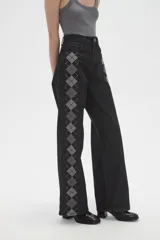 Pantalon de jean negro de corte ancho y tiro alto, con estampado de rombos en los laterales de las piernas.