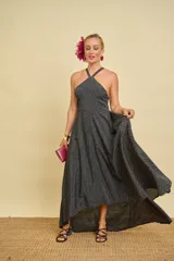 Vestido largo asimétrico color negro con estampado de lunares blancos, escote halter cruzado al frente y diseño con espalda descubierta.