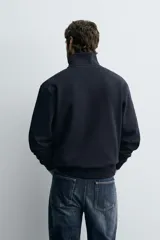 Sudadera roja de corte regular, con cuello alto y cierre frontal de cremallera. Manga larga y terminaciones en rib.