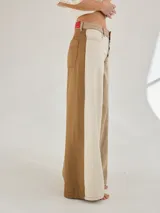 Pantalon ancho de denim en varios tonos de azul con diseño patchwork, de tiro medio y cierre frontal con botones.