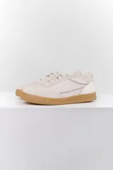 Zapatillas deportivas de cuero color blanco hueso con detalles bordados y suela color caramelo.