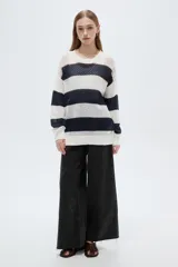Sweater de tejido de punto calado con diseño a rayas horizontales en color blanco y azul marino, cuello redondo y mangas largas.