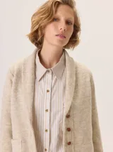 Saco de lana hervida con cuello solapa, cierre frontal de botones rústicos y bolsillos laterales. Presenta un diseño clásico con textura delicada y duradera.