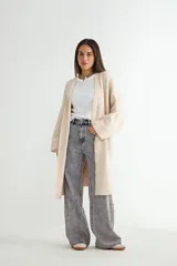 Saco tipo cárdigan largo de tejido de punto, color beige, con diseño abierto sin botones, mangas largas amplias y corte recto.