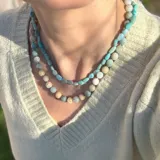 Collar de cuentas irregulares de piedra natural amazonita en tonos turquesa y verde agua, con cierre y detalles metálicos con baño de oro.